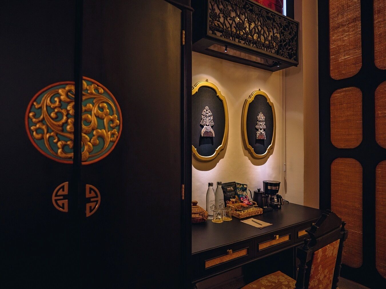 A room with a dark wooden desk, two ornate wall decorations, and a decorative railing.