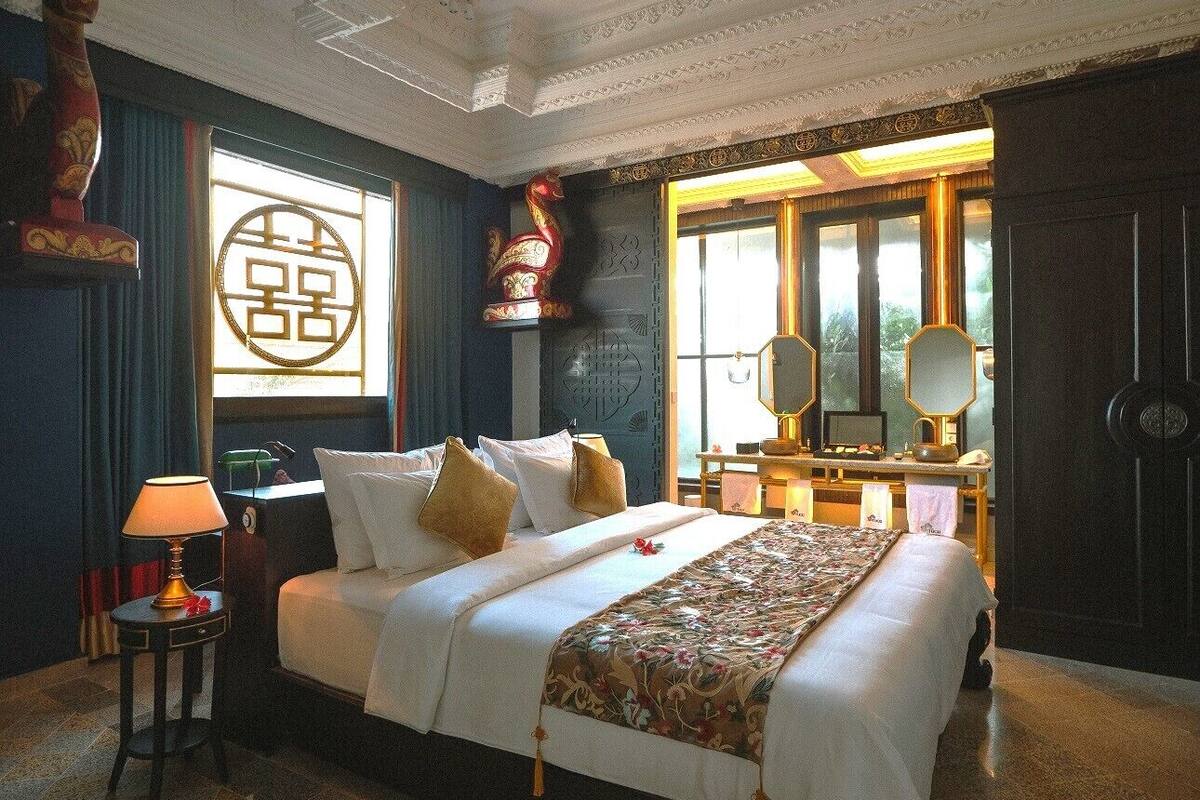 A well-appointed hotel room with a large bed, a desk with a lamp, a decorative wall piece, and a window with a view.
