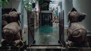 A courtyard with a central water feature, flanked by elephant statues and a staircase leading to an upper level.