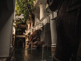 A grand hallway with a water feature, columns, and statues.