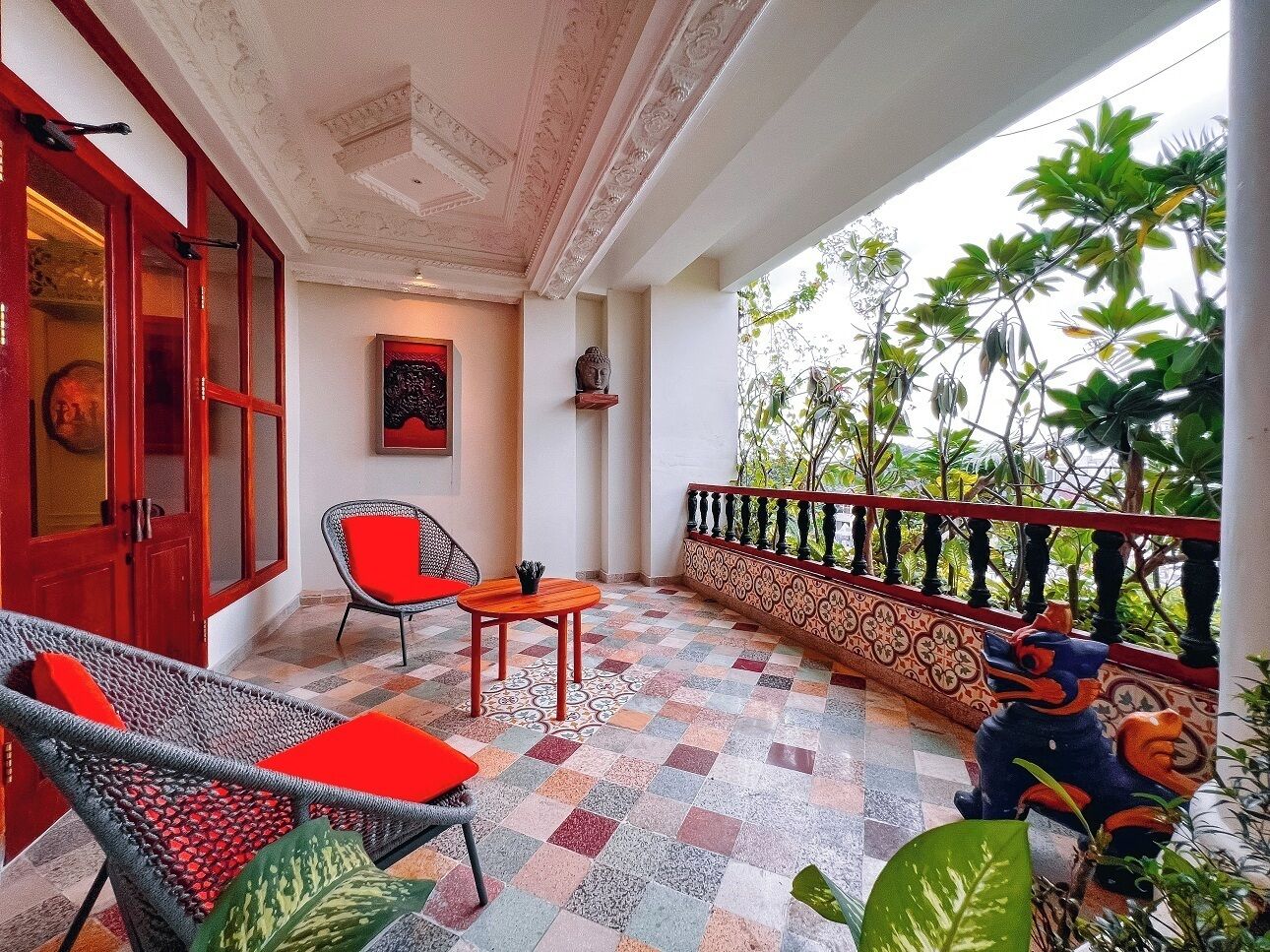 A balcony with a checkered floor, wicker furniture, and a decorative railing.