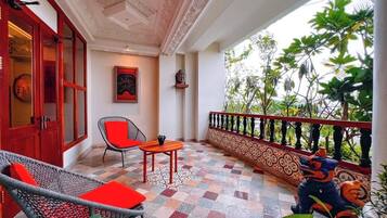 A balcony with a checkered floor, wicker furniture, and a decorative railing.