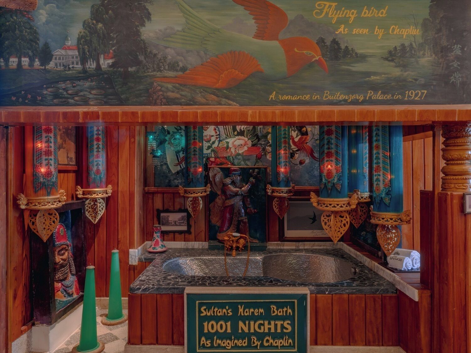 Una habitación con un mural de un pájaro volador, una estatua de un hombre y un letrero que dice "Baño del Harem del Sultán 1001 Noches Tal Como lo Imaginó Chaplin".