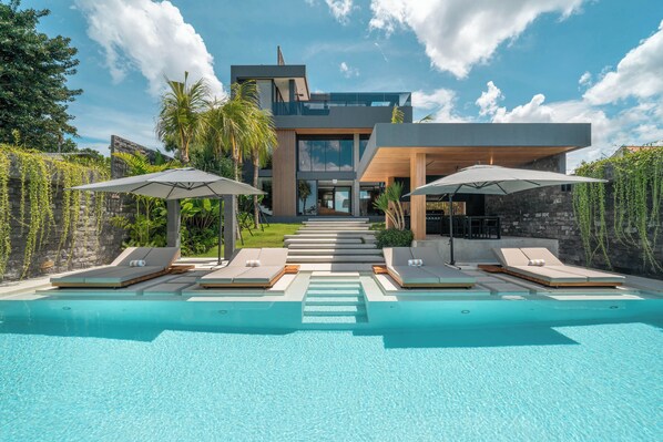 A modern house with a swimming pool, lounge chairs, and umbrellas. - Beyond The Palms (Canggu)