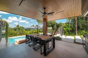 A modern outdoor dining area with a pool, wooden ceiling, and tropical garden views. - Beyond The Palms (Canggu)