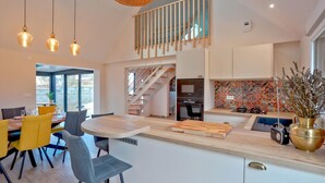 A modern kitchen with a central island, a dining area with yellow chairs, and a staircase leading to an upper level. - Awesome home in Flottemanville-hague with WiFi (Flottemanville-hague)