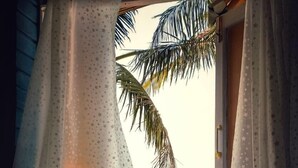 Une chambre avec vue sur l’océan, donnant sur une fenêtre ornée de rideaux à motifs étoilés.