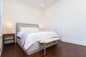 Une chambre à coucher avec un lit, des tables de chevet et un banc.