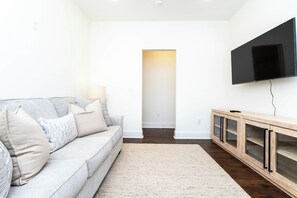 Un salon moderne avec un canapé, un téléviseur à écran plat et un meuble en bois.