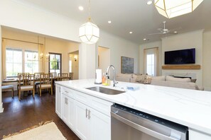 A modern kitchen with a central island, built-in dishwasher, and a dining area with wooden chairs.