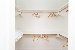 Un placard blanc avec des cintres en bois et une tringle en bois.