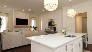 A modern living room with a large sofa, a dining area, and a kitchen with a central island. - Magnolia Manor by Apex Short Term Stays (Oxford)