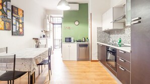 Une cuisine moderne avec un coin repas, une horloge au mur et un mur d’accent vert.