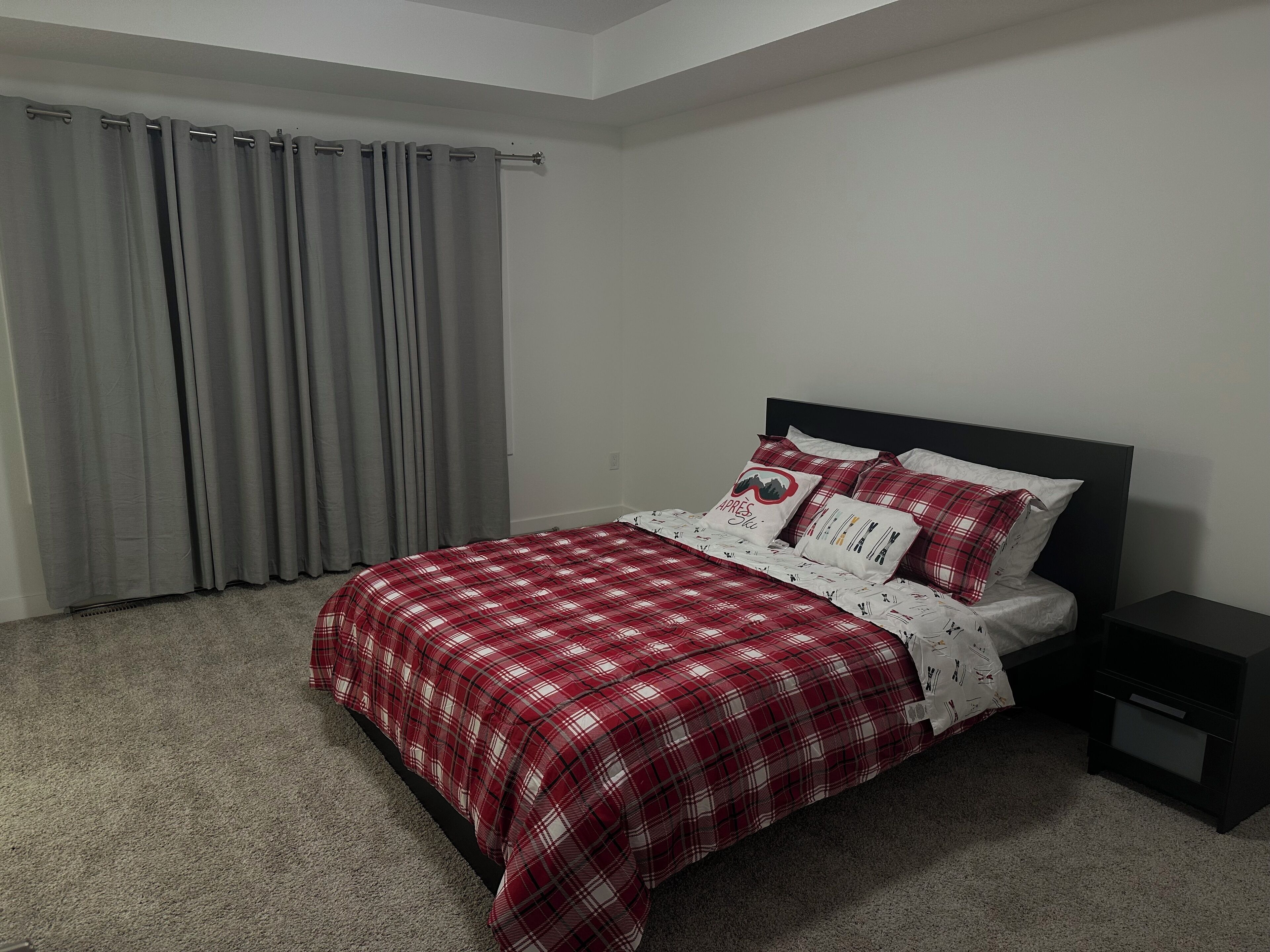 Une chambre à coucher avec un lit, des rideaux gris et une table de chevet.