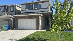 A two-story residential building with a garage, a brick accent wall, and a well-maintained lawn. - Spacious 3-Bedroom Apartment in  – Perfect for Groups & Families! (Calgary)