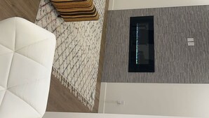 A modern living room with a striped sofa, a white armchair, and a patterned rug. - Spacious 3-Bedroom Apartment in  – Perfect for Groups & Families! (Calgary)