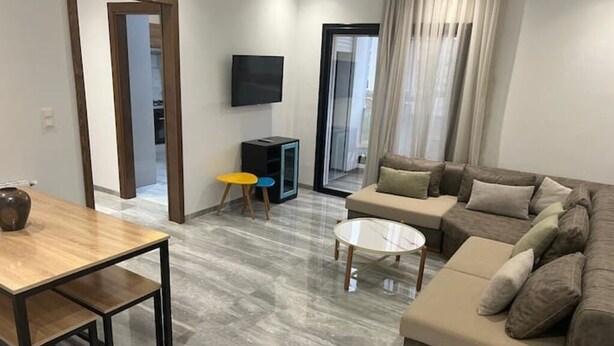 Una sala de estar moderna con un sofá, una mesa de centro, un televisor y una pequeña mesa con sillas.