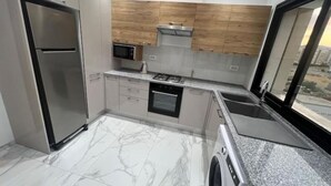 Una cocina moderna con un refrigerador de acero inoxidable, microondas, horno y lavadora.
