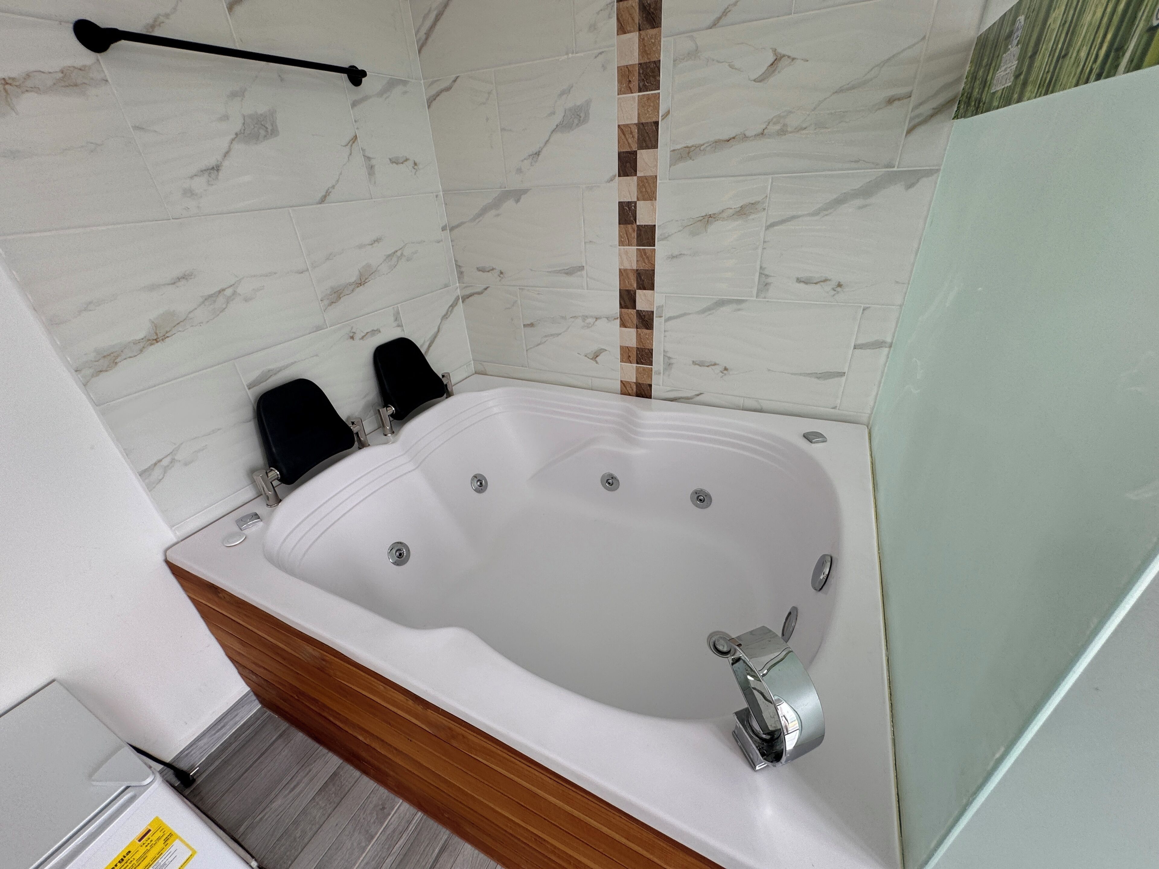Un baño moderno con una bañera independiente, un tocador de madera y un cerramiento de ducha de vidrio.