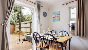 Ein Essbereich mit einem Holztisch und Stühlen, einer Uhr an der Wand und einem Fenster mit Vorhängen.