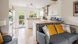 A modern kitchen with white cabinets, a central island, and a dining area with a sofa and cushions.
