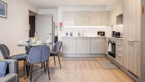 Une cuisine moderne dotée d’un îlot central, d’appareils électroménagers intégrés et d’un coin repas avec une table et des chaises.
