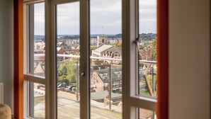 Une vue à travers une fenêtre donnant sur une ville, avec des bâtiments et une tour.