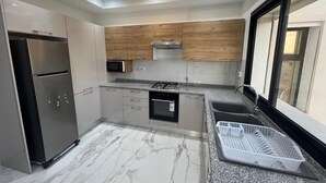 A modern kitchen with a built-in oven, microwave, and stainless steel refrigerator. - Superb Apartment S+2 Sahloul 4 Sousse (Sousse)