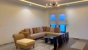 A modern living room with a sectional sofa, a glass coffee table, and a small side table. - Superb Apartment S+2 Sahloul 4 Sousse (Sousse)