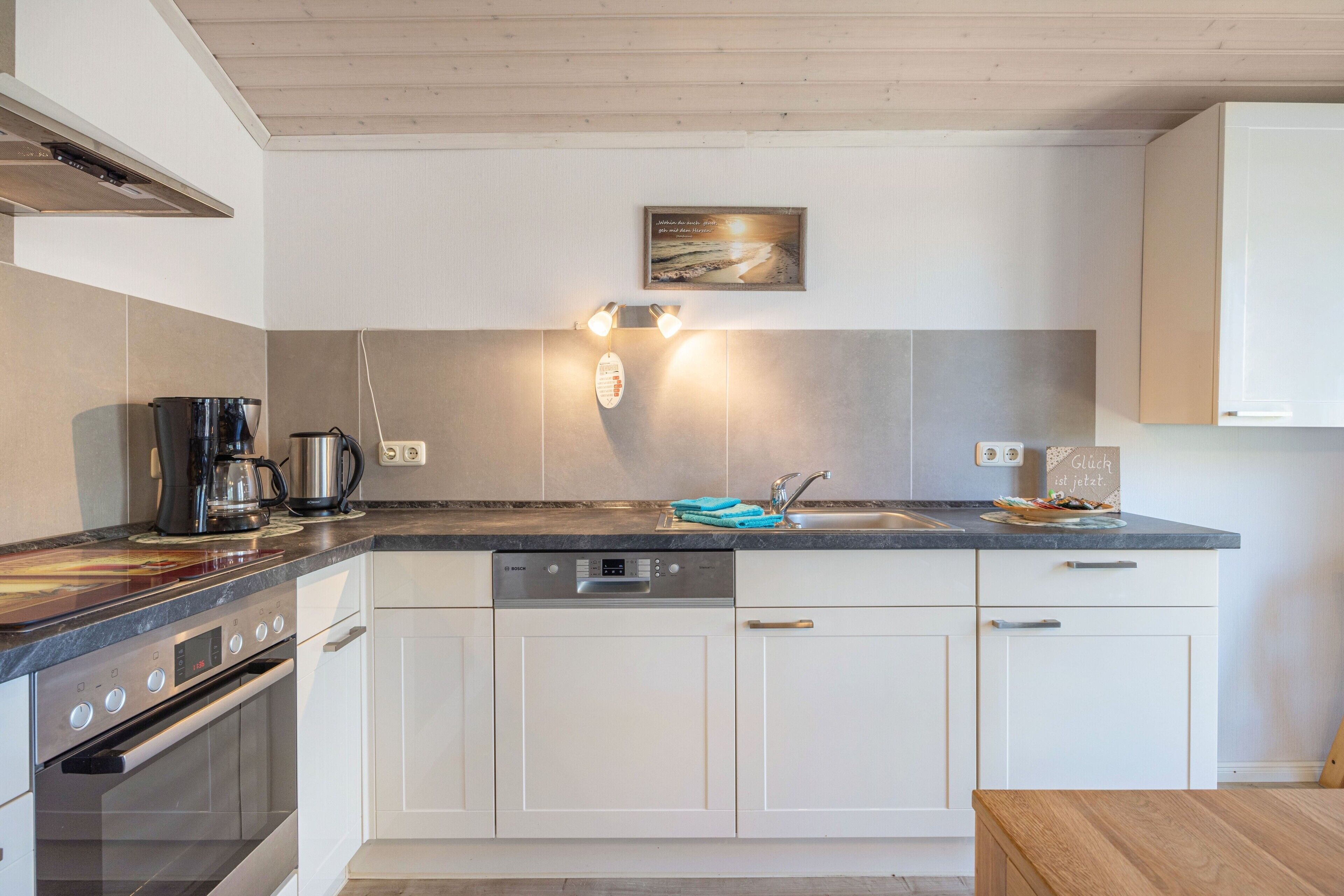 Eine moderne Küche mit Geschirrspüler, Backofen und Kaffeemaschine.