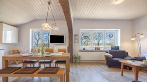 A spacious living area with a dining table, chairs, a sofa, and a TV.