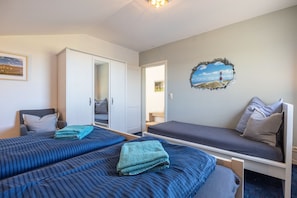 Une pièce avec deux lits, une chaise, une armoire et une porte donnant sur une autre pièce.