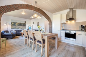 Une cuisine moderne avec une arche en briques, une table à manger en bois et des chaises.