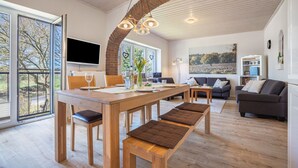 A spacious living area with a dining table, benches, a sofa, and a TV.
