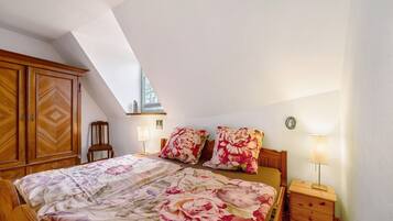 A bedroom with a bed, wooden wardrobe, nightstands, lamps, and a window.