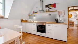 Een moderne keuken met witte kasten, een inbouwoven, een roestvrijstalen afzuigkap en houten aanrechtbladen.