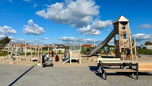 Ein Spielplatz mit Rutsche, Klettergeräten und Bänken.