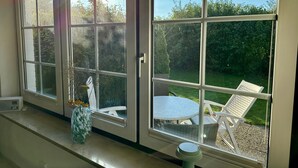 Ein Zimmer mit einer großen Schiebeglasdoor, die auf eine Terrasse mit Tisch und Stühlen führt.