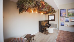 A room with a piano, a white chair, a small table, and a hanging floral arrangement. - L'indret del Pedraforca (Saldes)
