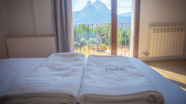 A neatly made bed with two towels, one labeled "Cinderella" and the other "Cinderella." - L'indret del Pedraforca (Saldes)