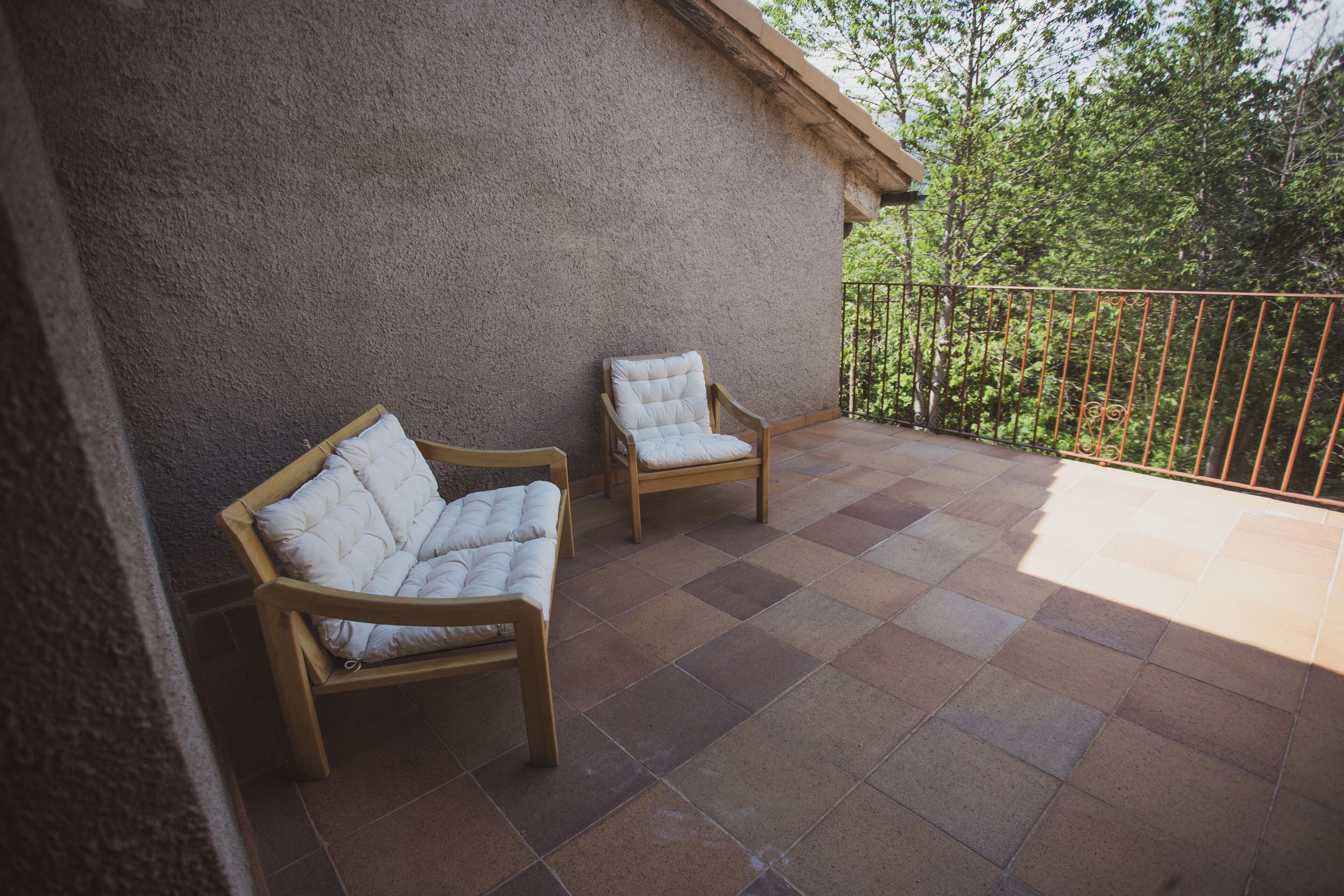 A balcony with two wooden chairs and a tiled floor.