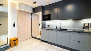 Una cocina moderna con gabinetes grises, un microondas negro, un lavamanos con grifo negro y una cafetera.