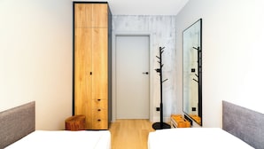 Una habitación de hotel moderna con un armario grande, un espejo y un taburete de madera pequeño.