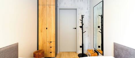 A modern hotel room with a large wardrobe, a mirror, and a small wooden stool.