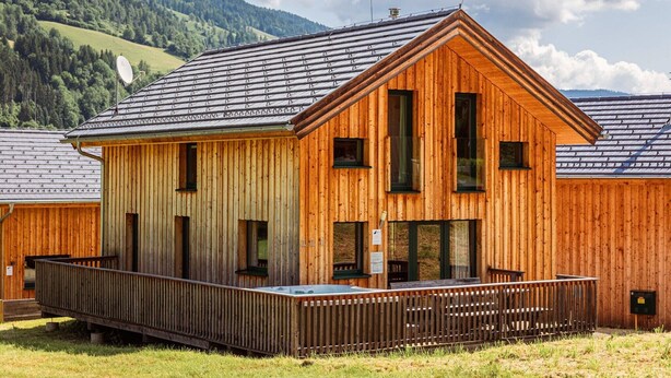A wooden cabin with a balcony, large windows, and a metal roof. - Modern chalet with infrared sauna (Sankt Georgen am Kresichberg)