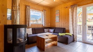 A cozy cabin interior with a wooden interior, a sofa, a coffee table, and a fireplace. - Modern chalet with infrared sauna (Sankt Georgen am Kresichberg)