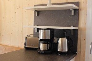 Una cocina con un tostador, una cafetera y una tetera sobre la encimera.