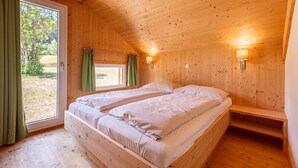 A wooden cabin room with two beds, a window with curtains, and a bench. - Modern chalet with infrared sauna (Sankt Georgen am Kresichberg)
