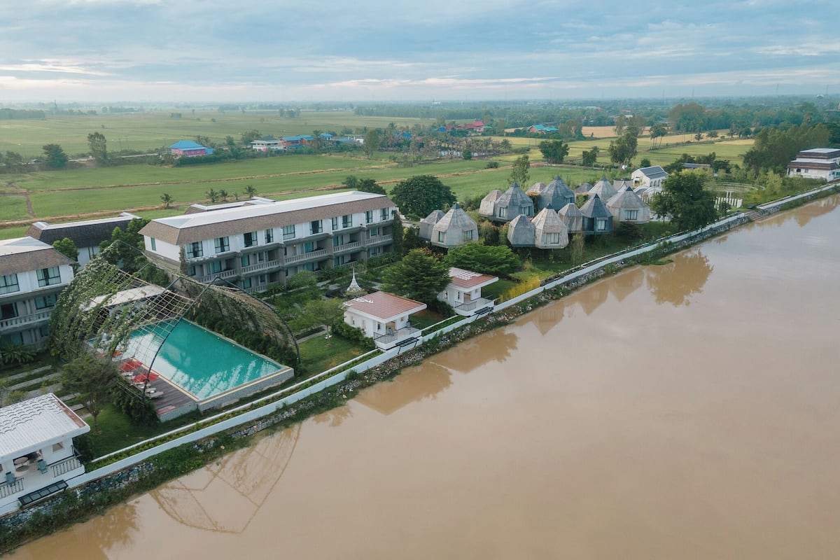 Ein Hotel am Flussufer mit Schwimmbad, mehreren Gästezimmern und Blick auf die umliegende Landschaft.