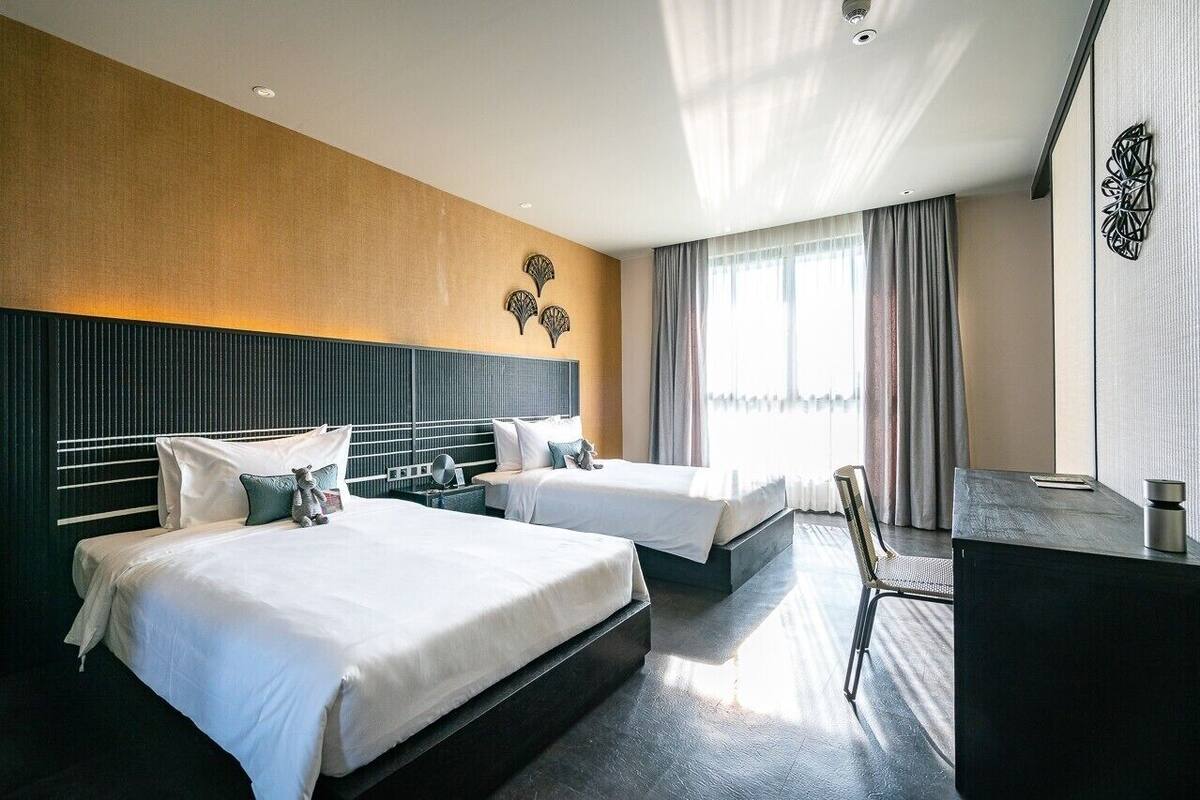 Ein Hotelzimmer mit zwei Betten, einem Schreibtisch und einem Stuhl.